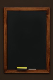 Clean black chalkboard hanging on brown wall