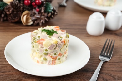 Photo of Traditional russian salad Olivier served on wooden table