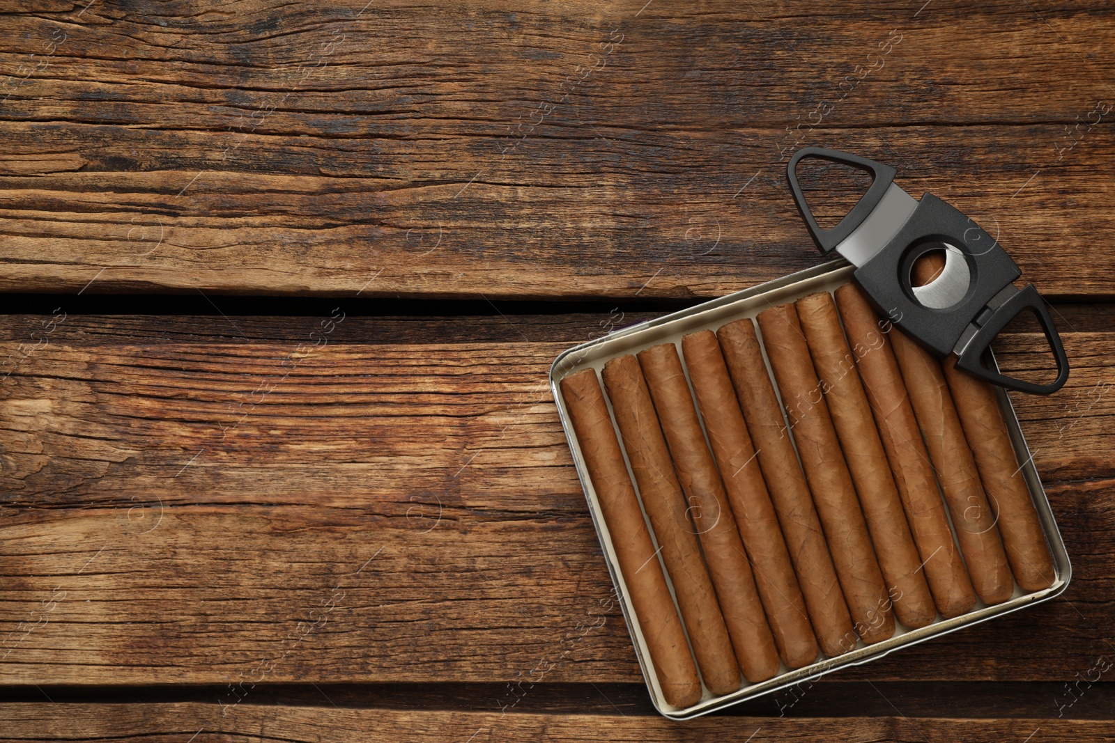 Photo of Cigars and guillotine cutter on wooden table, top view. Space for text