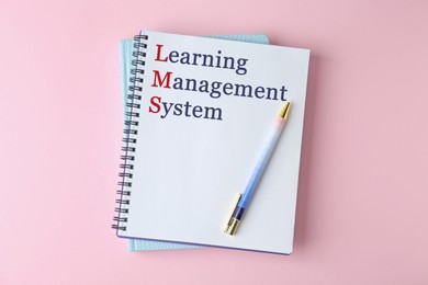Image of Notebook with text Learning Management System and red initial letters forming initialism LMS on pink background, top view