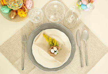 Photo of Festive table setting with decorated eggs, flat lay
