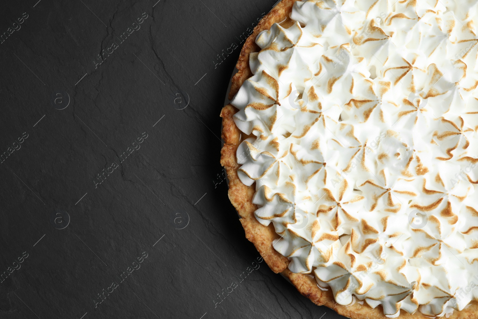 Photo of Delicious lemon meringue pie on black table, top view. Space for text