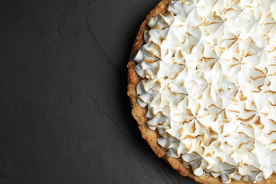 Photo of Delicious lemon meringue pie on black table, top view. Space for text