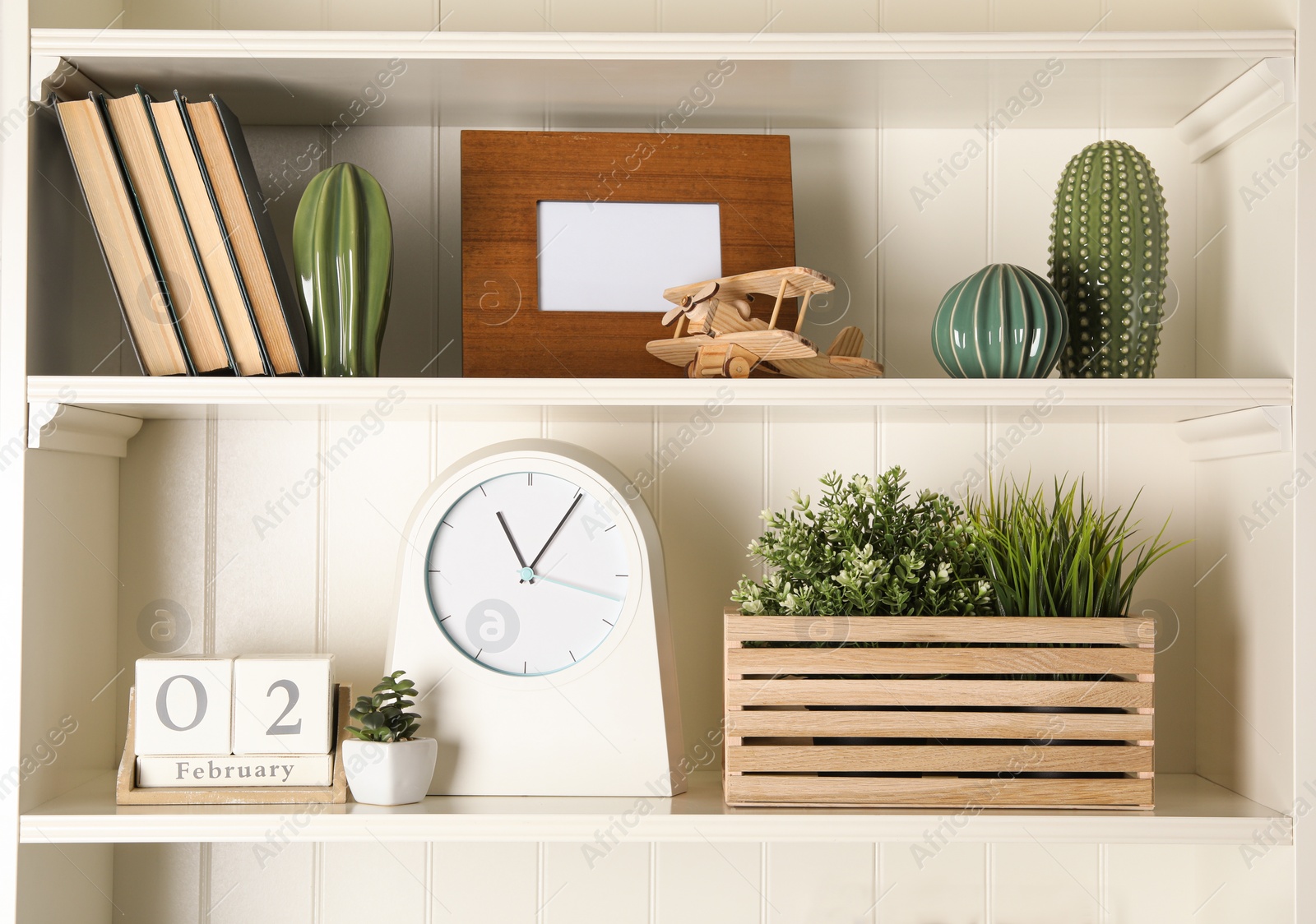 Photo of White shelving unit with clock and different decorative elements