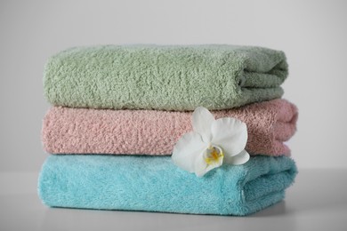 Stacked soft colorful towels with flower on white table