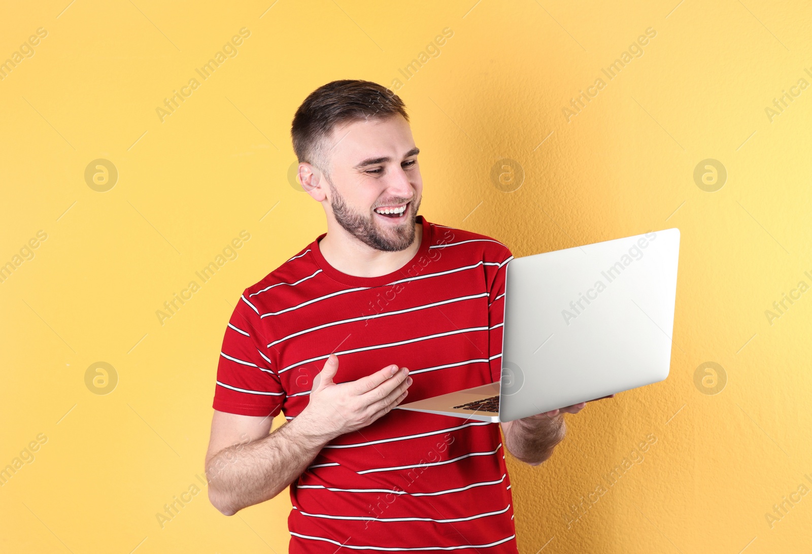 Photo of Young man using video chat on laptop against color background