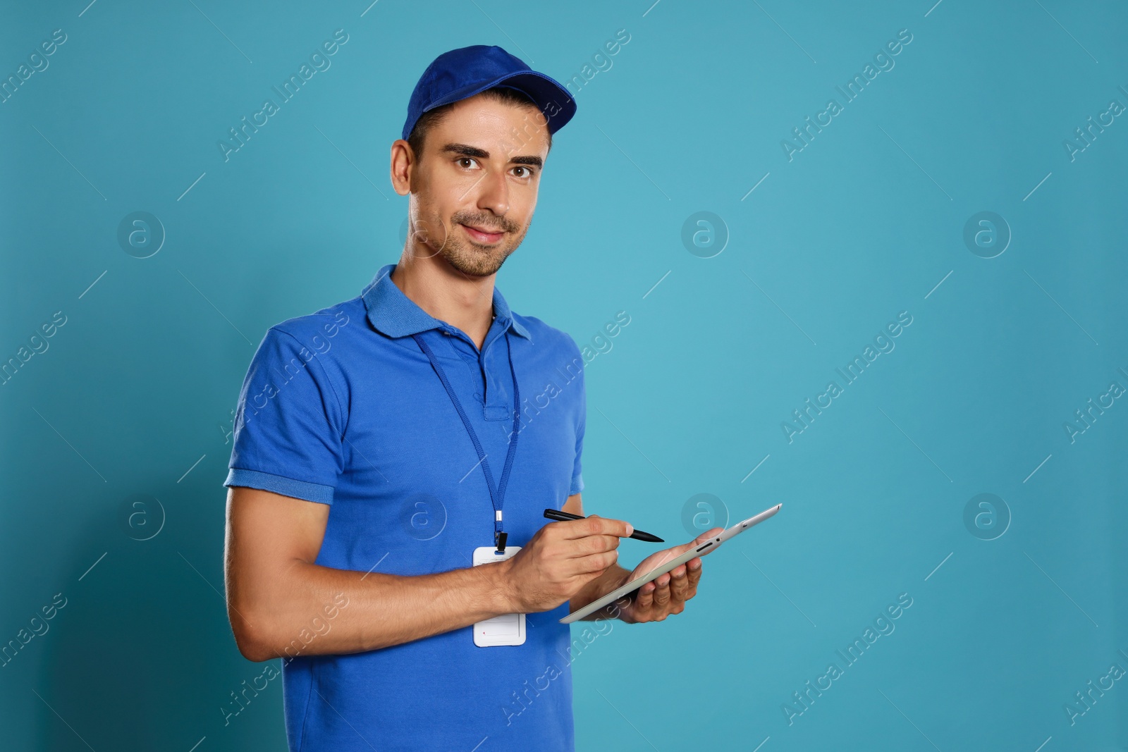 Photo of Happy young courier with tablet on blue background. Space for text