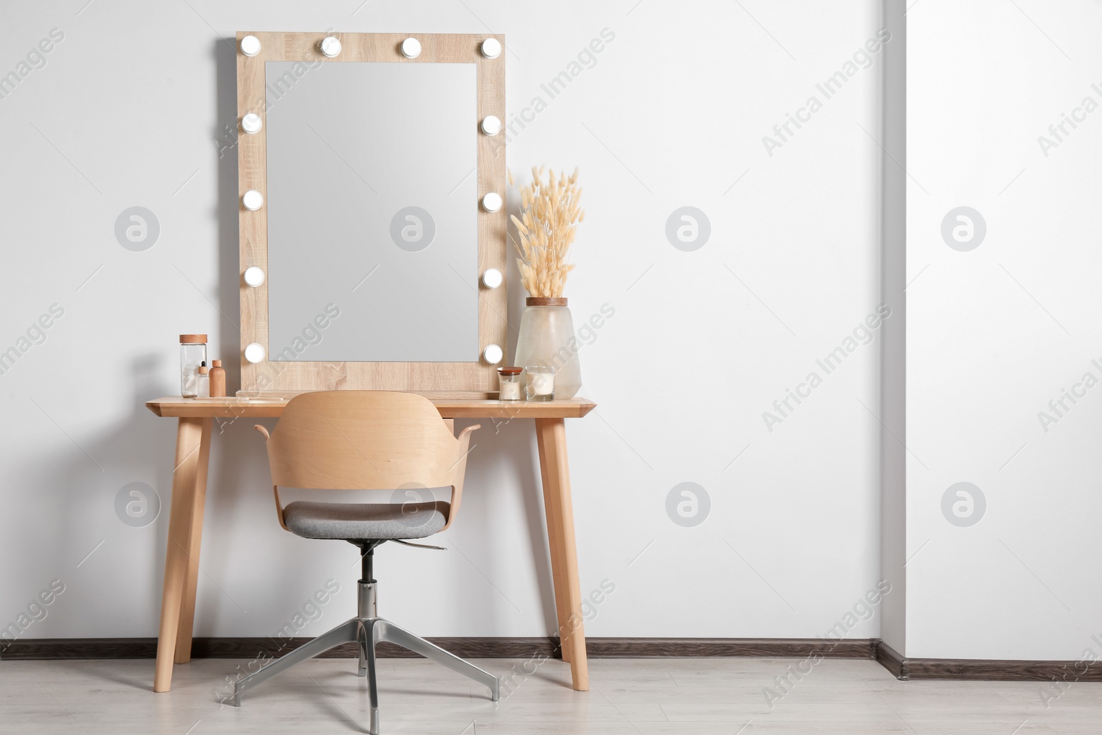 Photo of Dressing table with stylish mirror, dried reeds and other decorative elements. Interior design