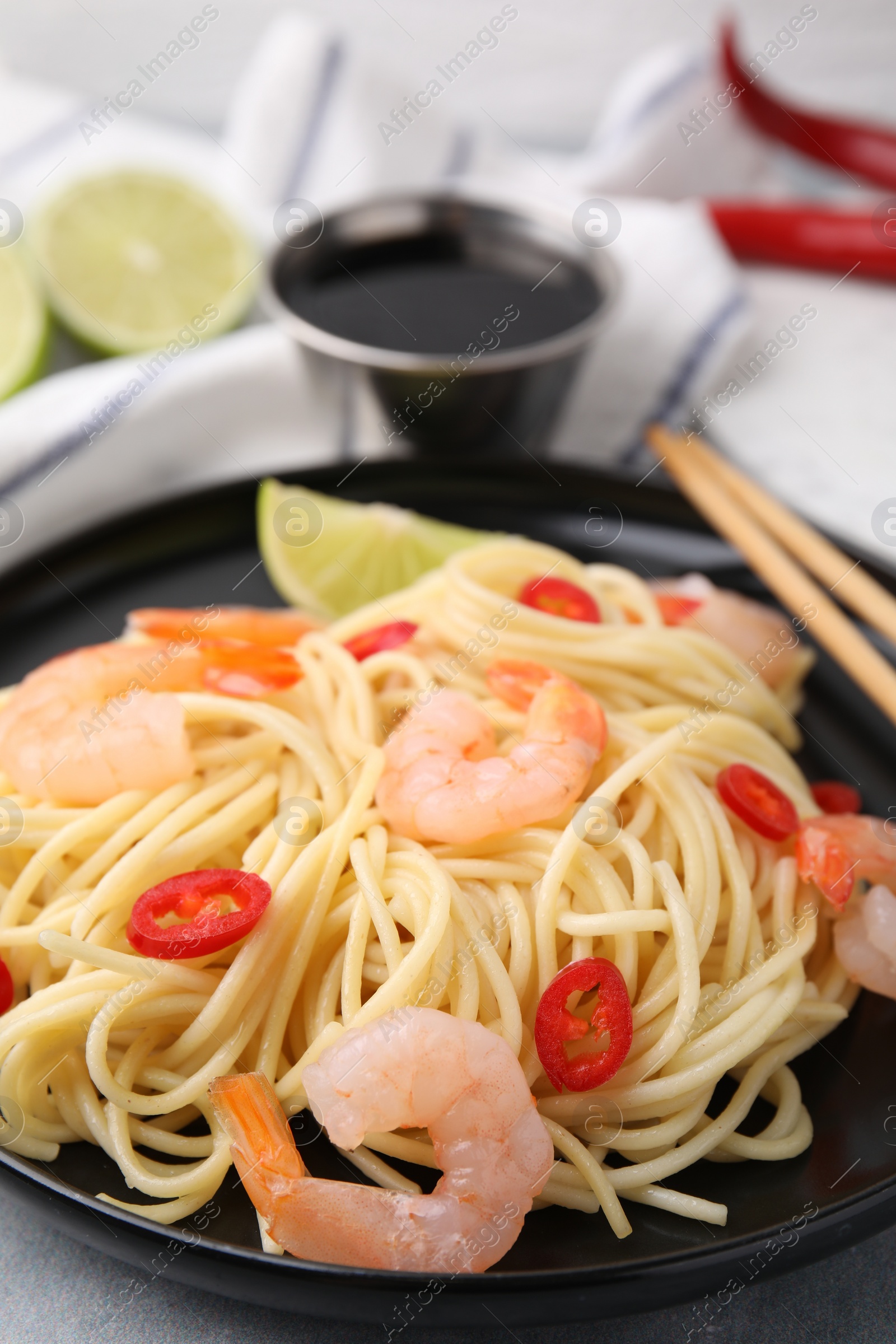 Photo of Tasty spaghetti with shrimps and chili pepper on grey table, closeup