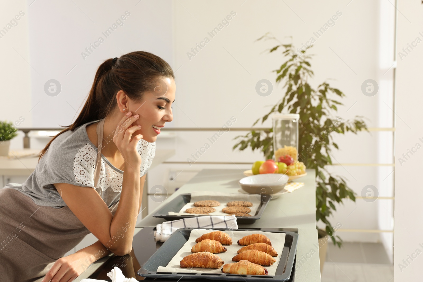 Photo of Young woman with homemade oven baked pastry  in kitchen