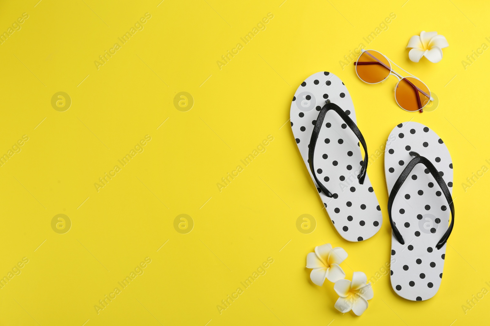 Photo of Flat lay composition with flip flops on yellow background. Space for text