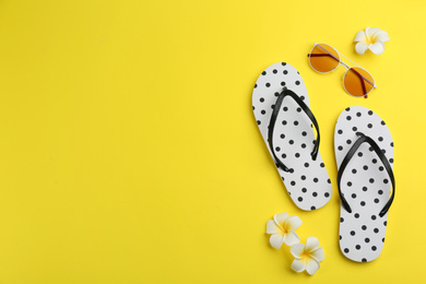 Flat lay composition with flip flops on yellow background. Space for text