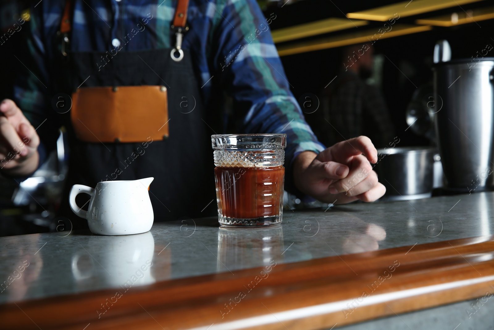 Photo of Barman with White Russian cocktail at counter in pub, closeup. Space for text