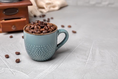 Ceramic cup with coffee beans on gray table