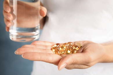 Woman with fish oil pills and glass of water, closeup