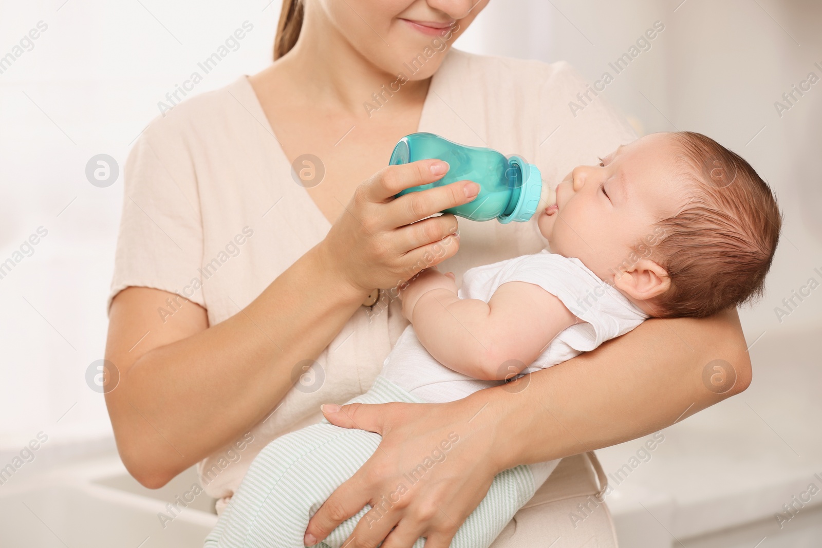 Photo of Mother feeding her cute child with infant formula indoors