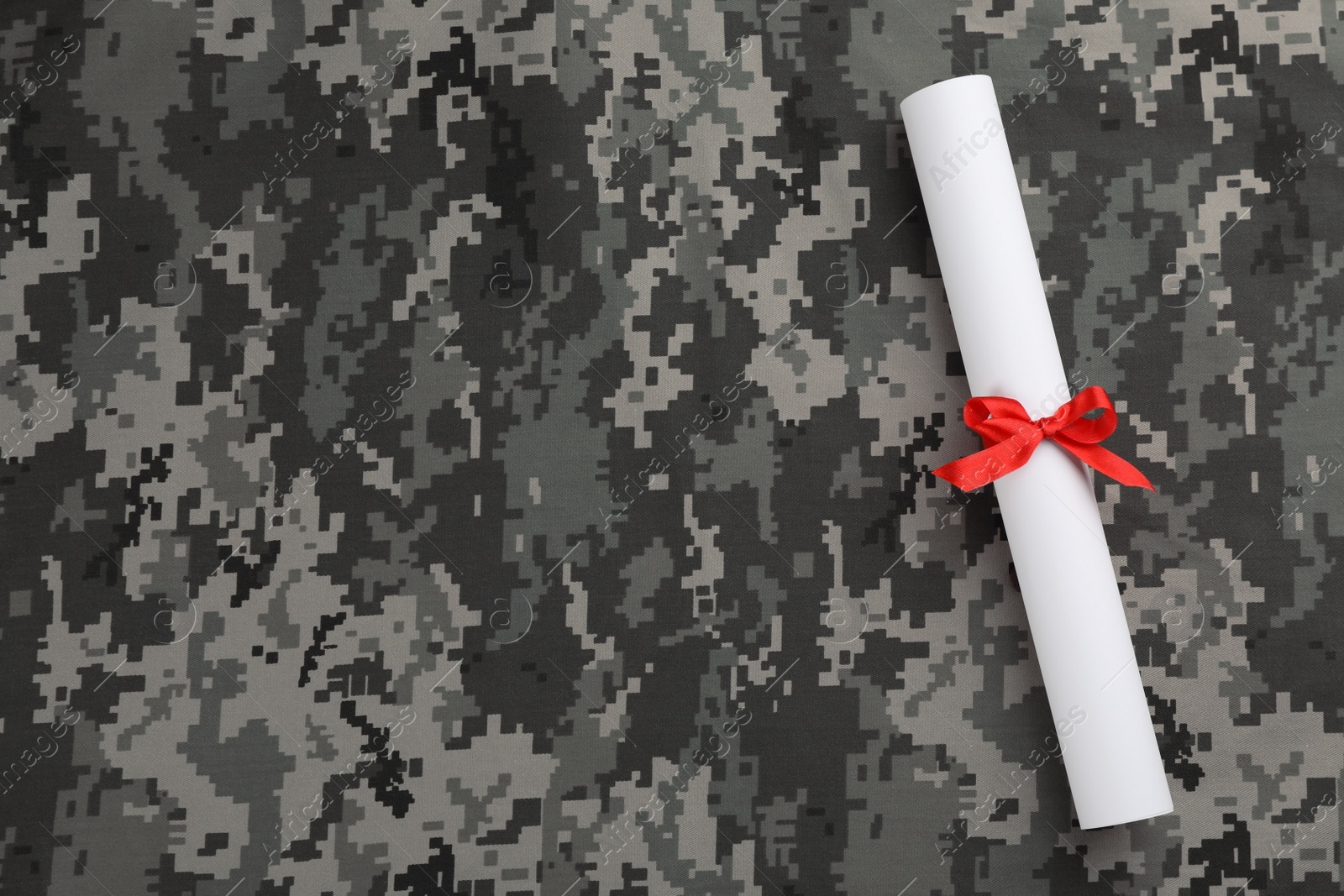 Photo of Top view of diploma with red ribbon on camouflage background, space for text. Military education