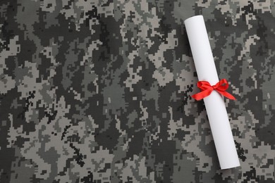 Top view of diploma with red ribbon on camouflage background, space for text. Military education