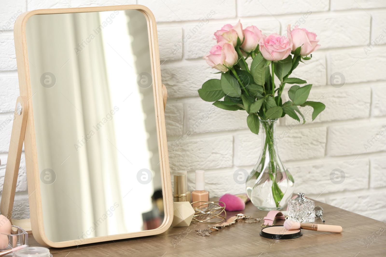 Photo of Different makeup products and accessories on dressing table in room interior