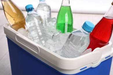 Photo of Blue plastic cool box with ice cubes and refreshing drinks, closeup
