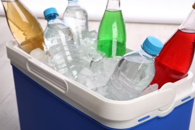 Blue plastic cool box with ice cubes and refreshing drinks, closeup