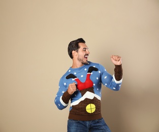 Photo of Happy young man in Christmas sweater on beige background