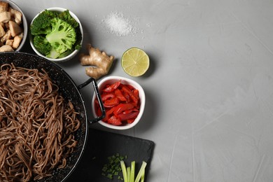 Photo of Wok with noodles, chicken and other products on light grey table, flat lay. Space for text