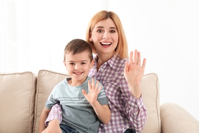 Mother and her son using video chat against light background, view from web camera