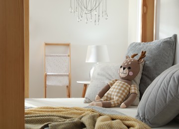 Photo of Comfortable wooden house bed with cushions and toy in child room. Interior design