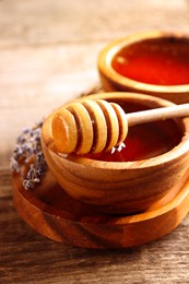 Image of Natural honey in wooden bowl and dipper on table, closeup