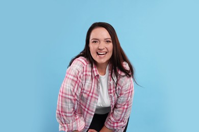 Beautiful overweight woman with charming smile on turquoise background