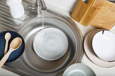 Washing plate in kitchen sink, above view