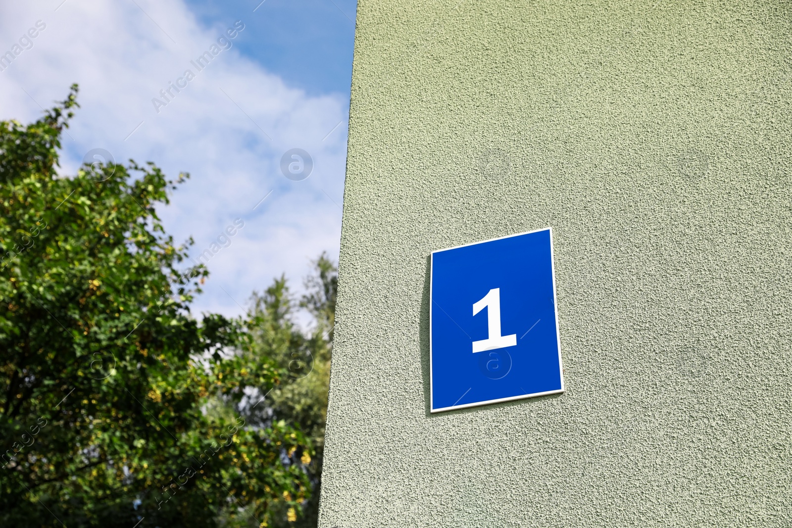 Photo of House number 1 on light green textured wall outdoors. Space for text
