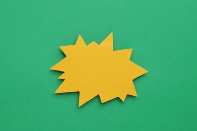 Photo of Paper bursting speech star on green background, top view. Space for text