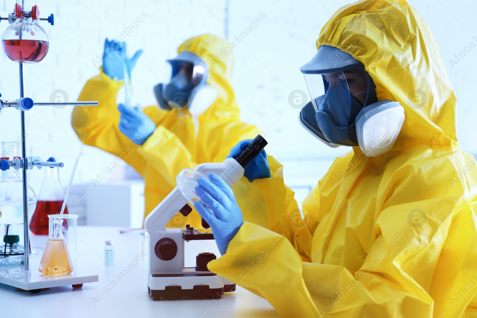 Photo of Scientist in chemical protective suit using microscope at laboratory. Virus research