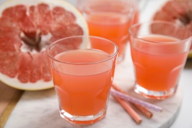 Photo of Glasses of pink pomelo juice on white table, closeup