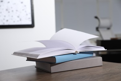 Photo of Stack of different hardcover books on wooden table indoors