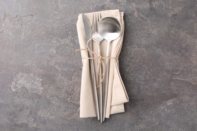 Set of stylish cutlery and napkin on grey textured table, top view