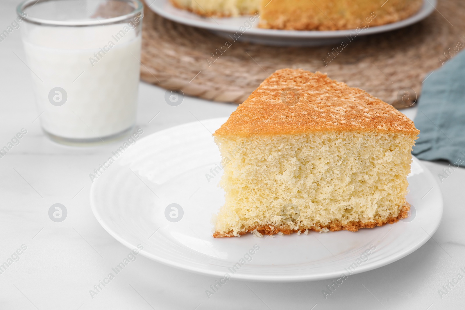 Photo of Plate with piece of tasty sponge cake on white marble table