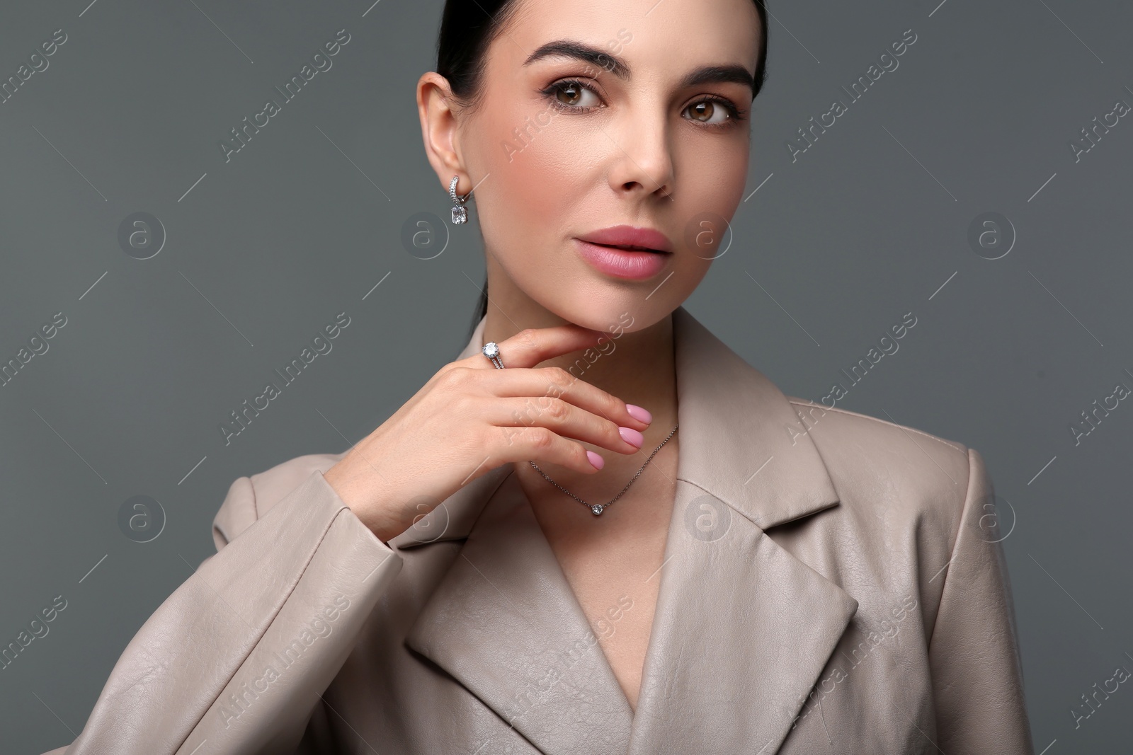 Photo of Beautiful young woman with elegant jewelry on dark grey background