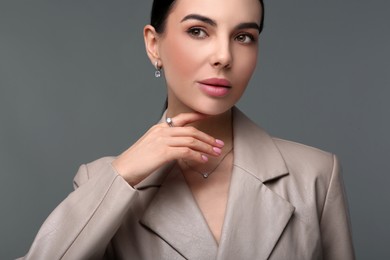 Photo of Beautiful young woman with elegant jewelry on dark grey background