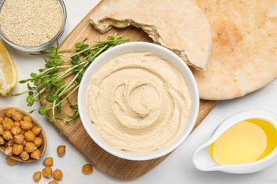 Photo of Delicious hummus and different ingredients on white marble table, flat lay