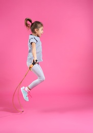 Photo of Active girl jumping rope on color background