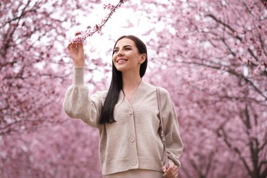 Photo of Pretty young woman in park with blooming trees. Spring look