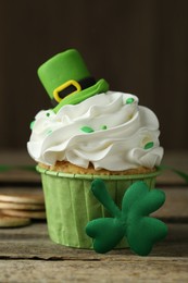 St. Patrick's day party. Tasty cupcake with green leprechaun hat topper on wooden table, closeup