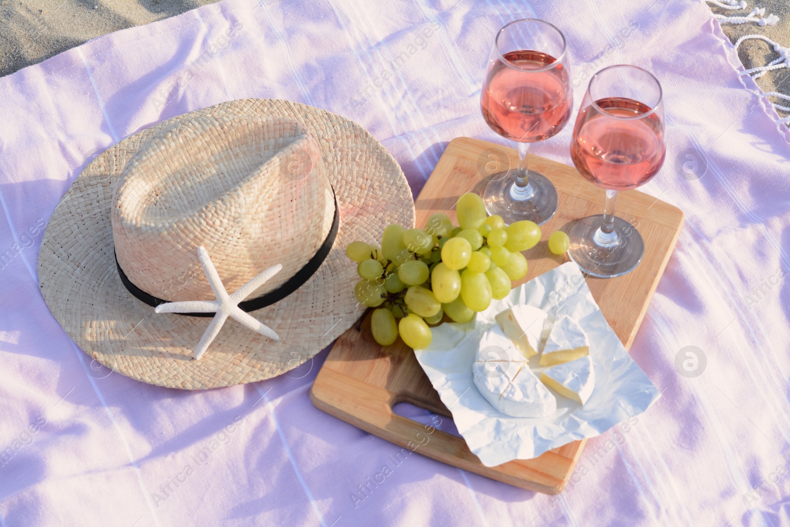 Photo of Glasses with rose wine and snacks on picnic blanket outdoors