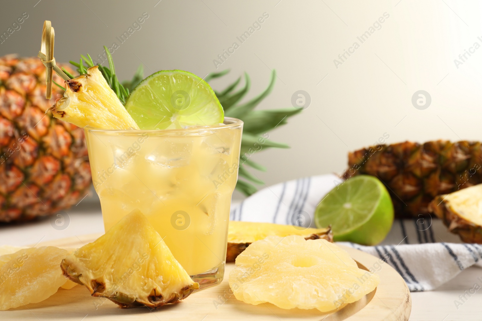 Photo of Glass of tasty pineapple cocktail and sliced fruits on table