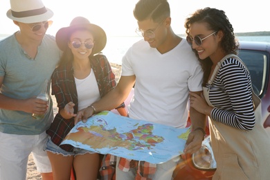Photo of Happy friends with map near car outdoors on sunny day. Summer trip