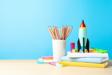 Bright toy rocket and school supplies on wooden table. Space for text