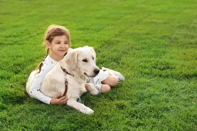 Photo of Cute little child with his pet on green grass